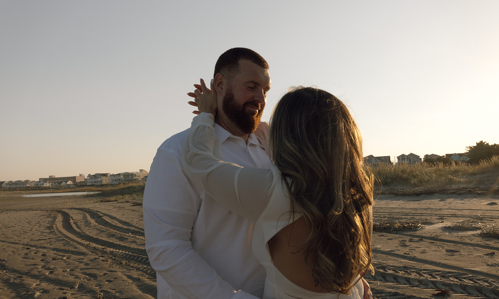 A couple holds each other during their engagement session in New Jersey on the beach