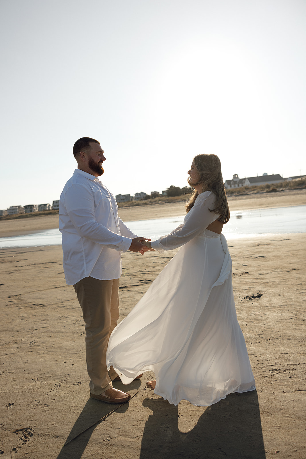 A couple laughs during their engagement session in New Jersey on the beach