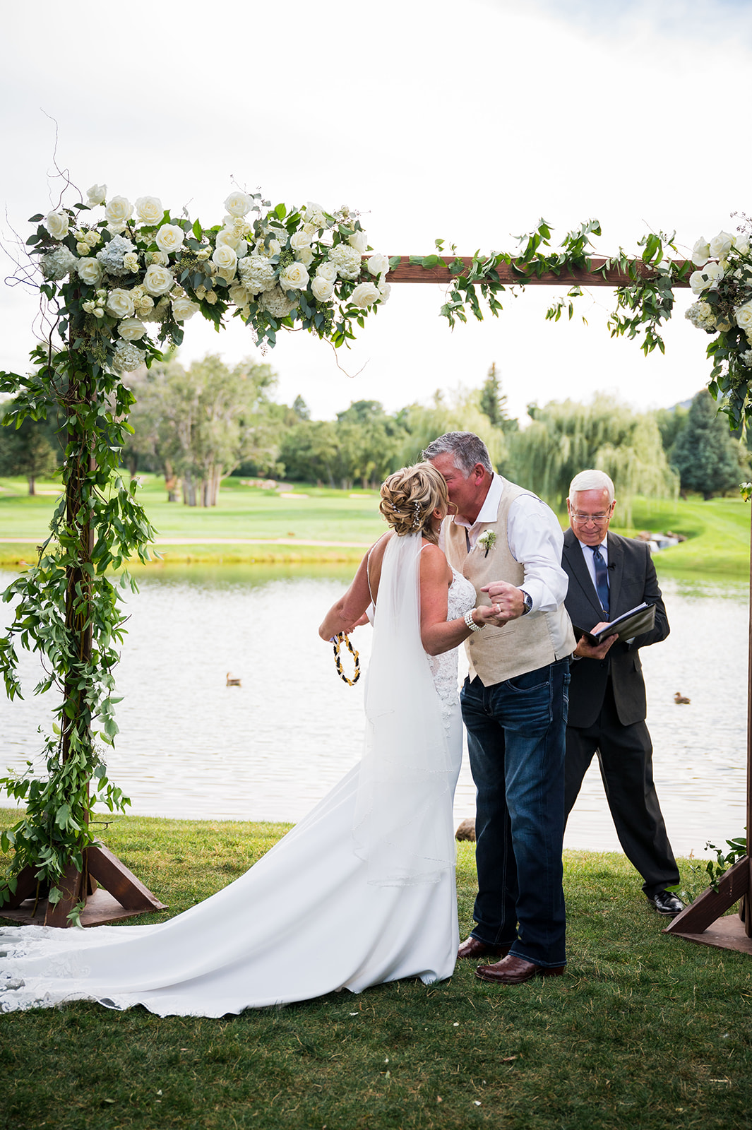 The bride and groom share their first kiss under the wedding arch.