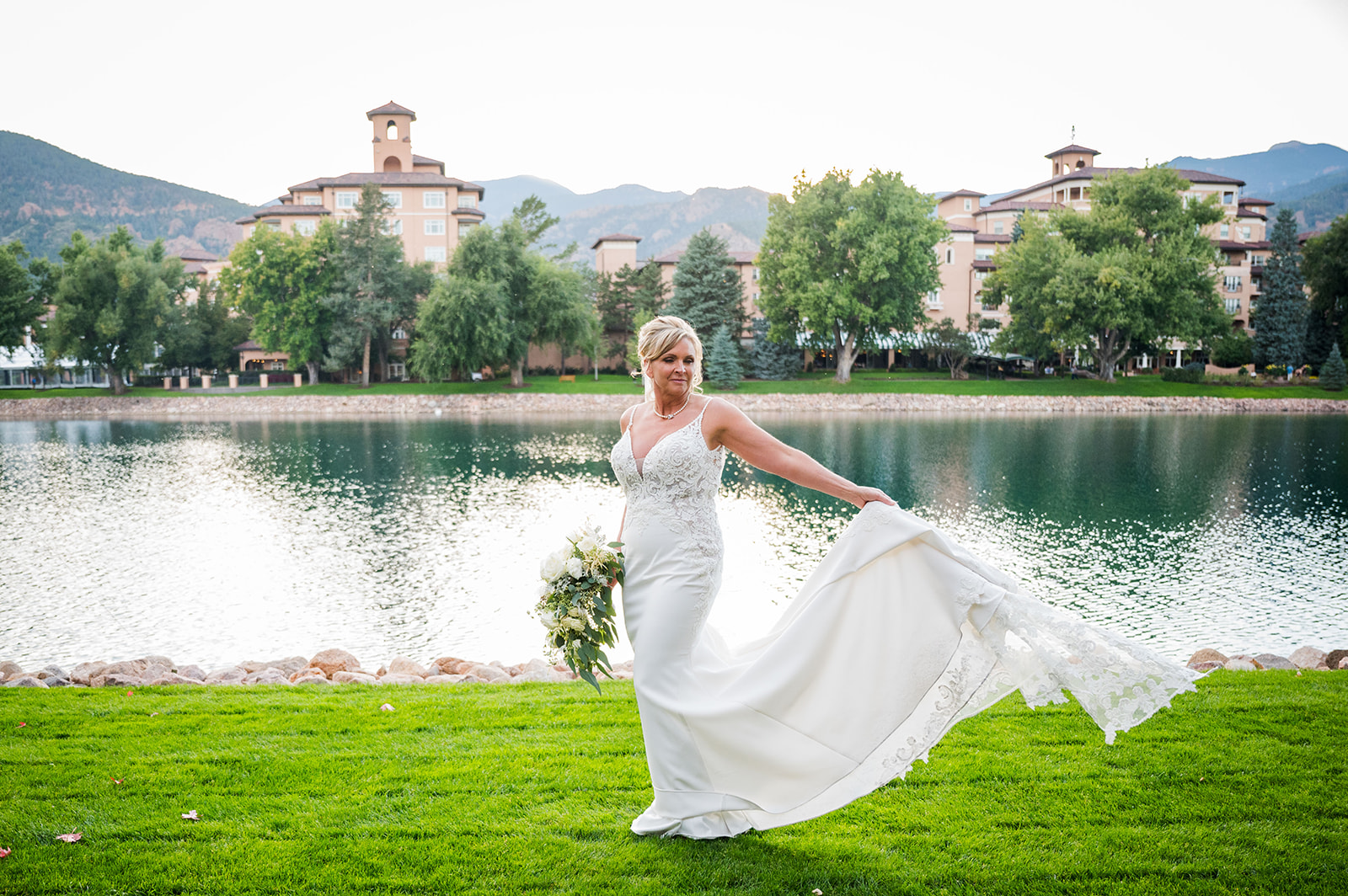 The bride twirls in her dress with the Broadmoor Hotel and lake in the background.