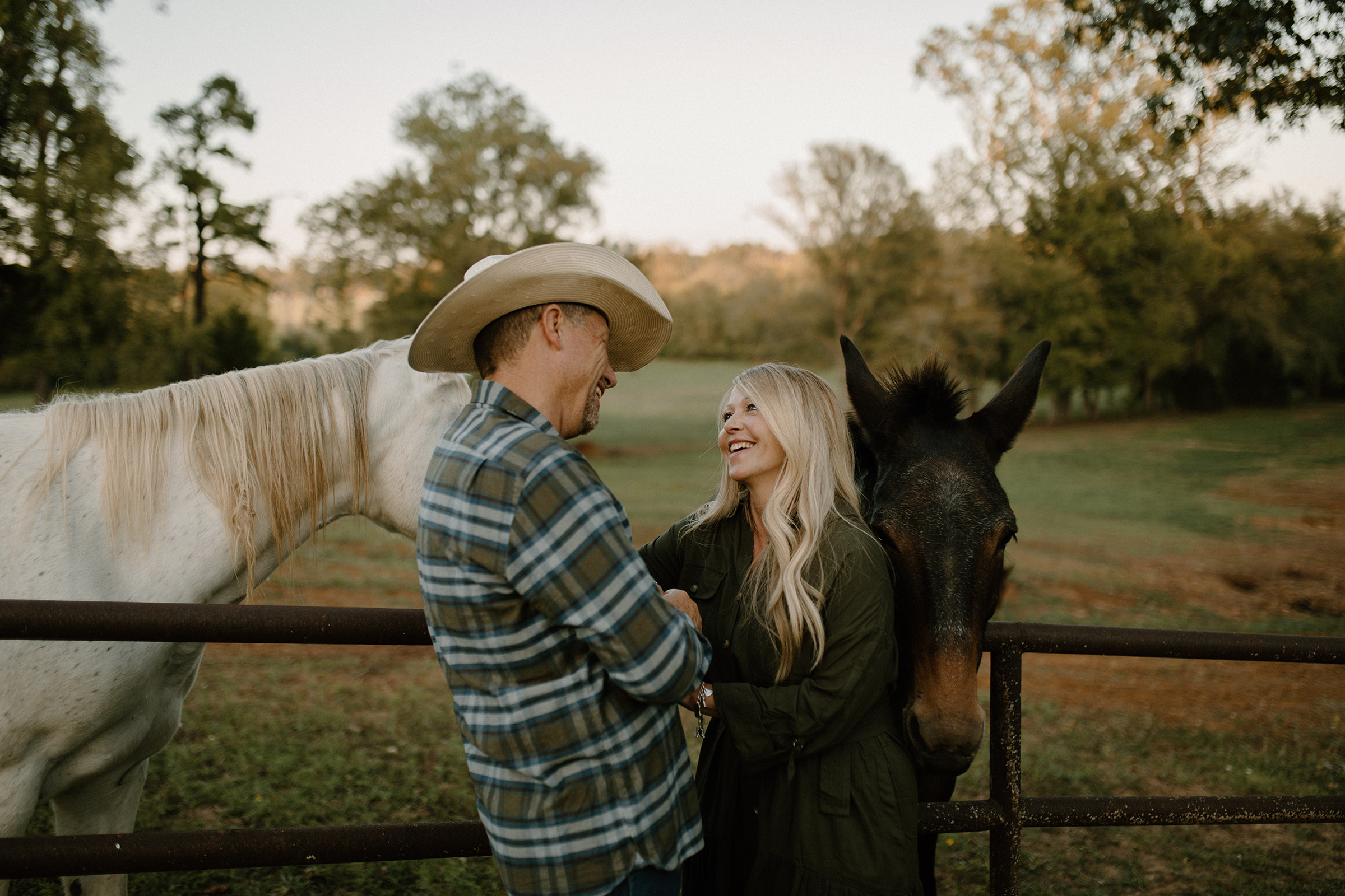 A couple next to their horses during their backyard engagement session in East Texas.