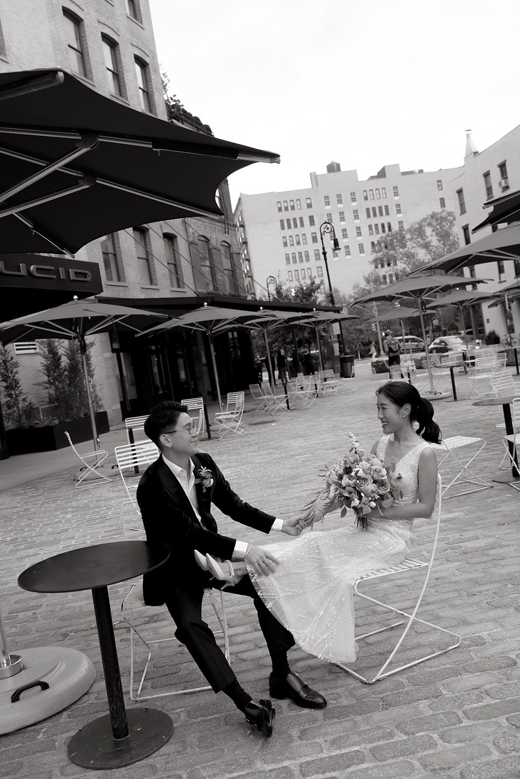 A couple sits together and laughs on their wedding day in Chelsea, NYC