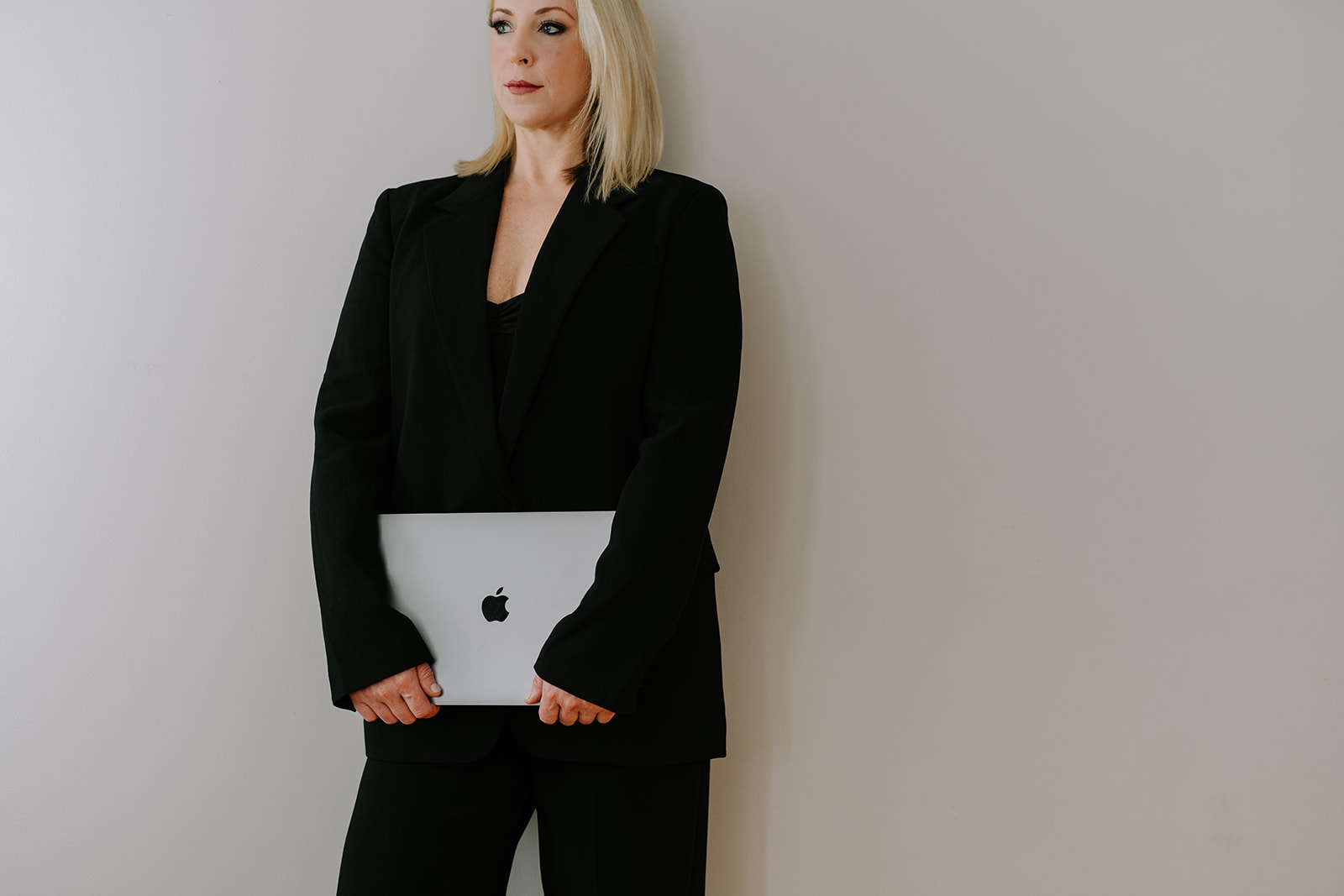 woman in black power suit with laptop