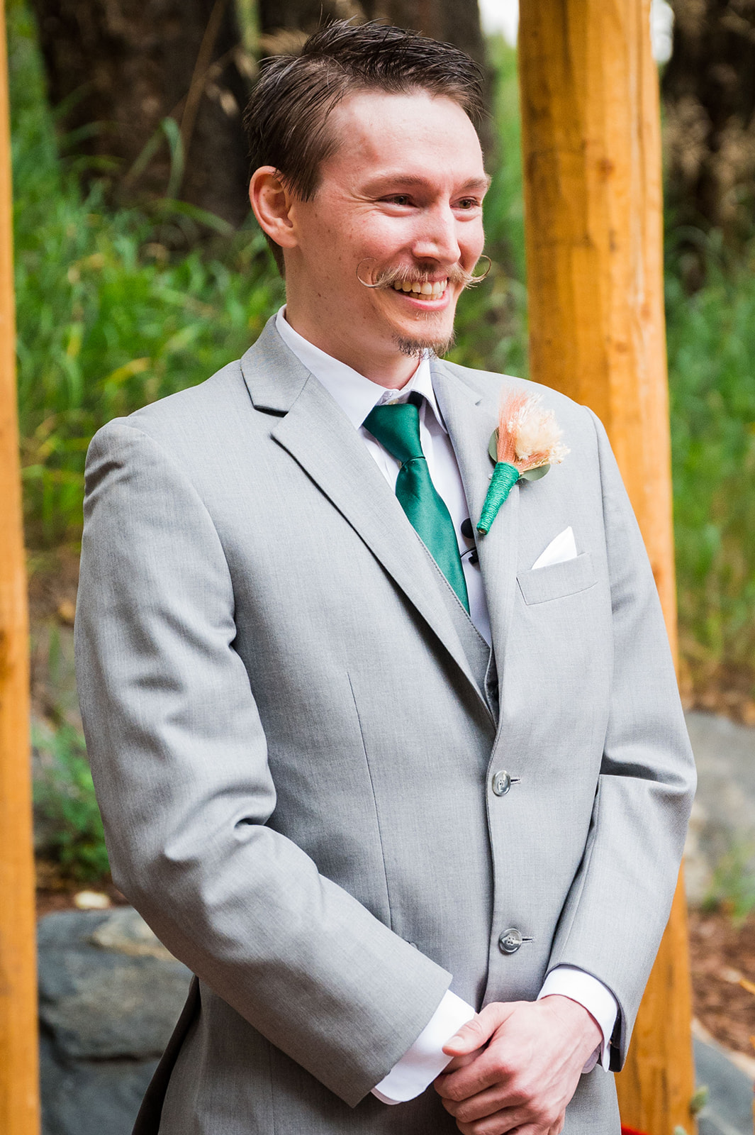 A groom smiles as he watches his bride walk down the aisle, captured by Denver wedding photographer Two One Photography.