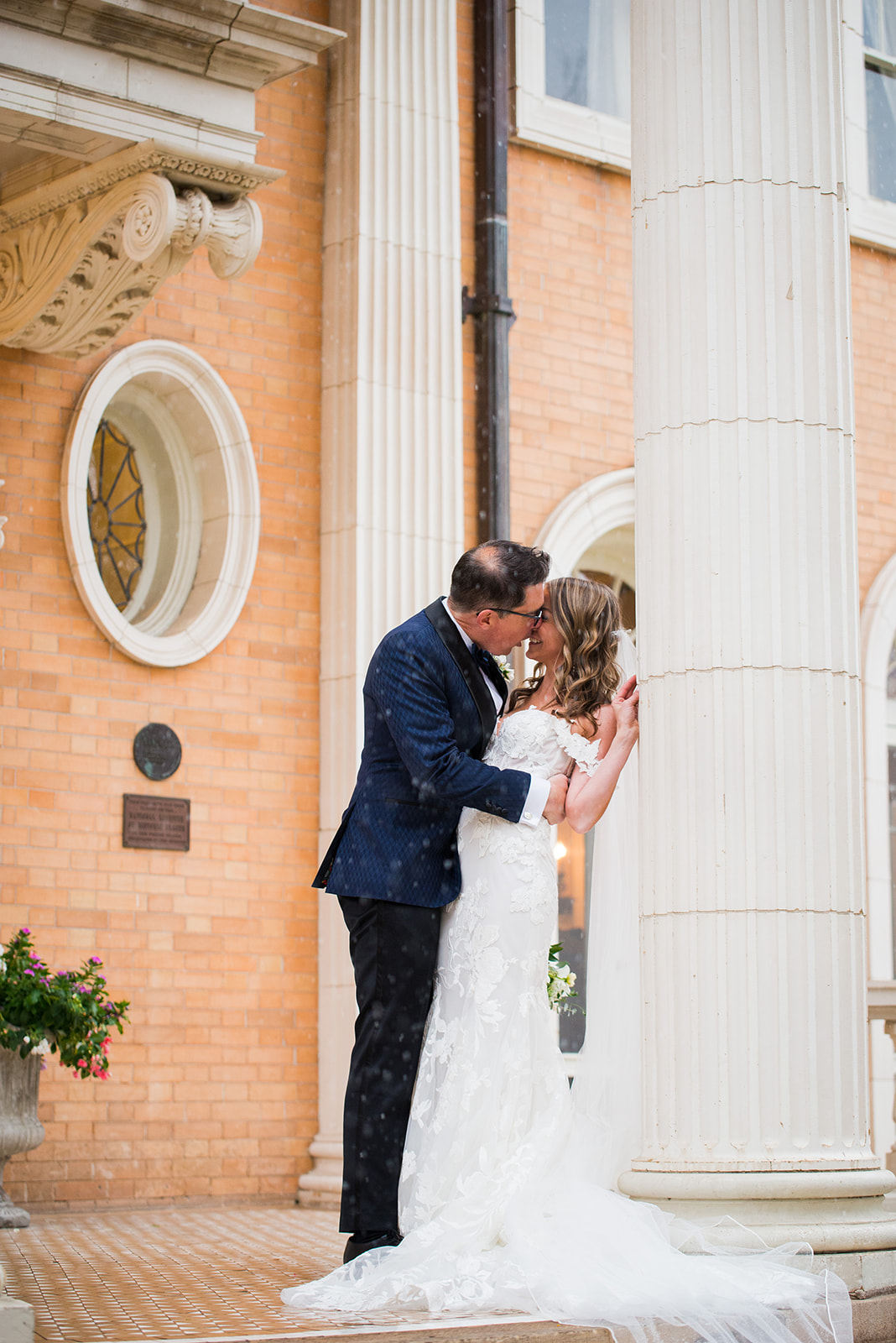 A groom dips his bride for a kiss standing on the front porch of the Grant Humphrey Mansion in Denver.