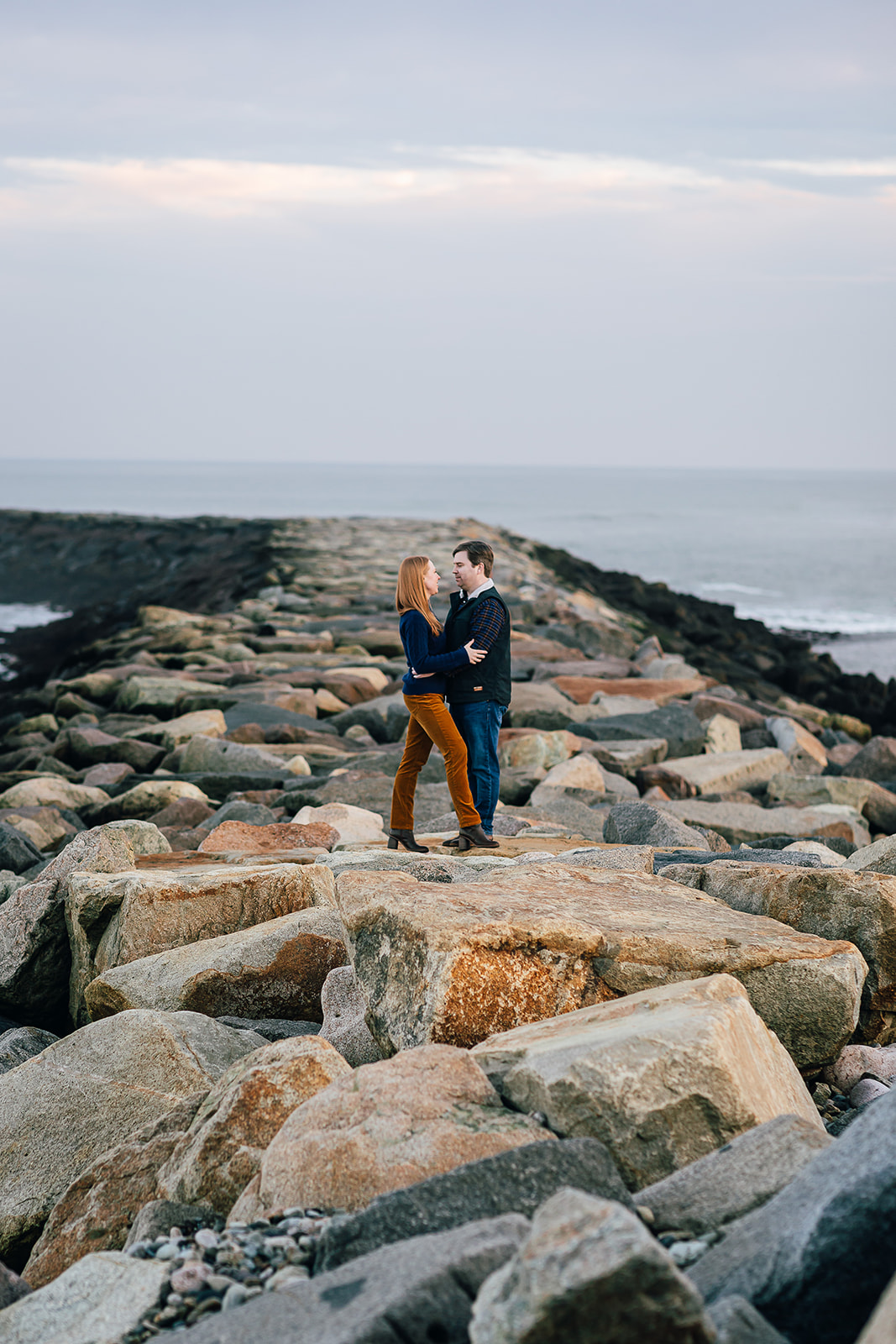 Engaged couple kisses on the jetty at the lighthouse in Scituate Massachusetts 