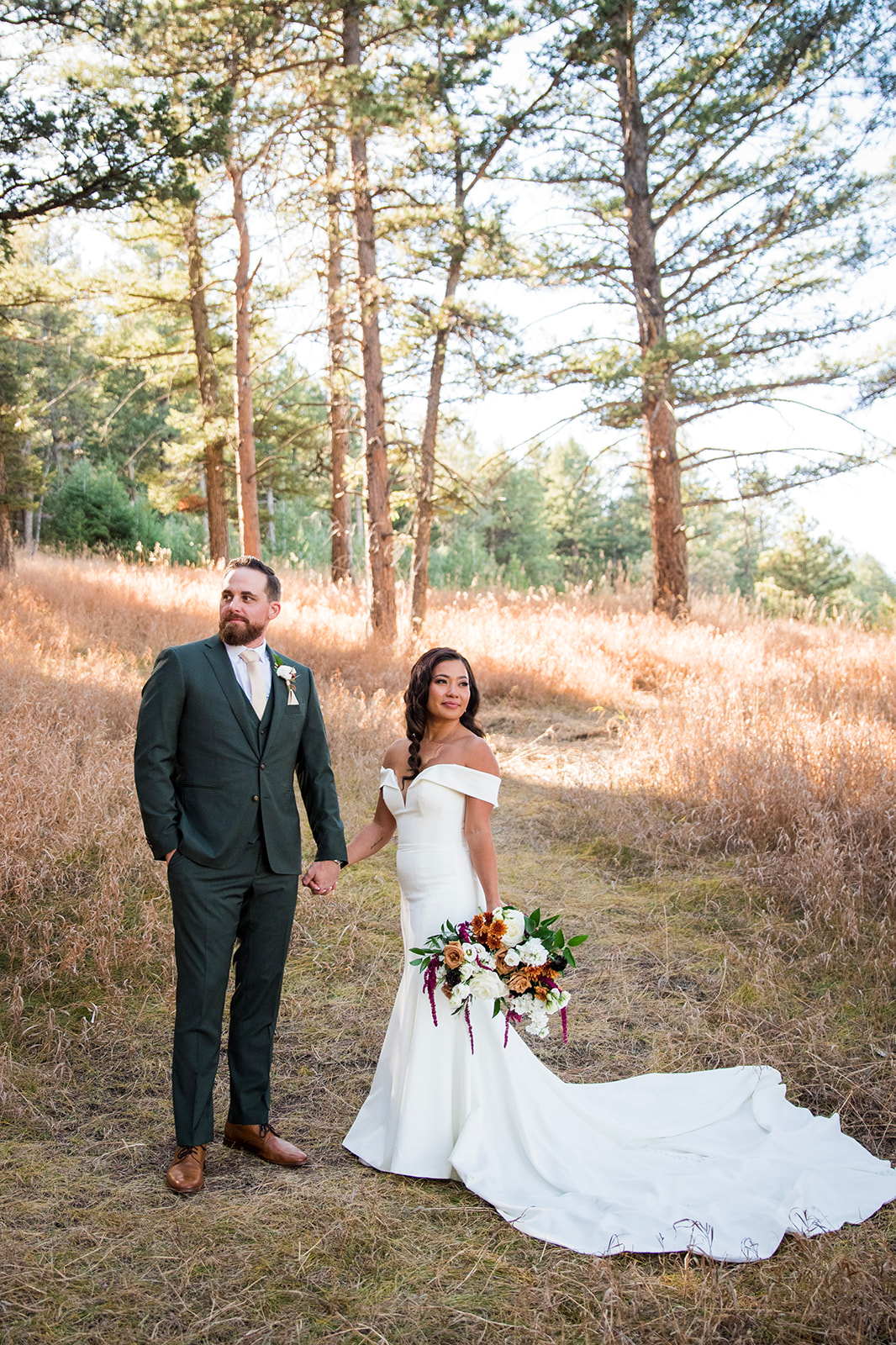 A bride and groom look seriously in opposite directions, standing in the pine forest at The Pines at Genesee.