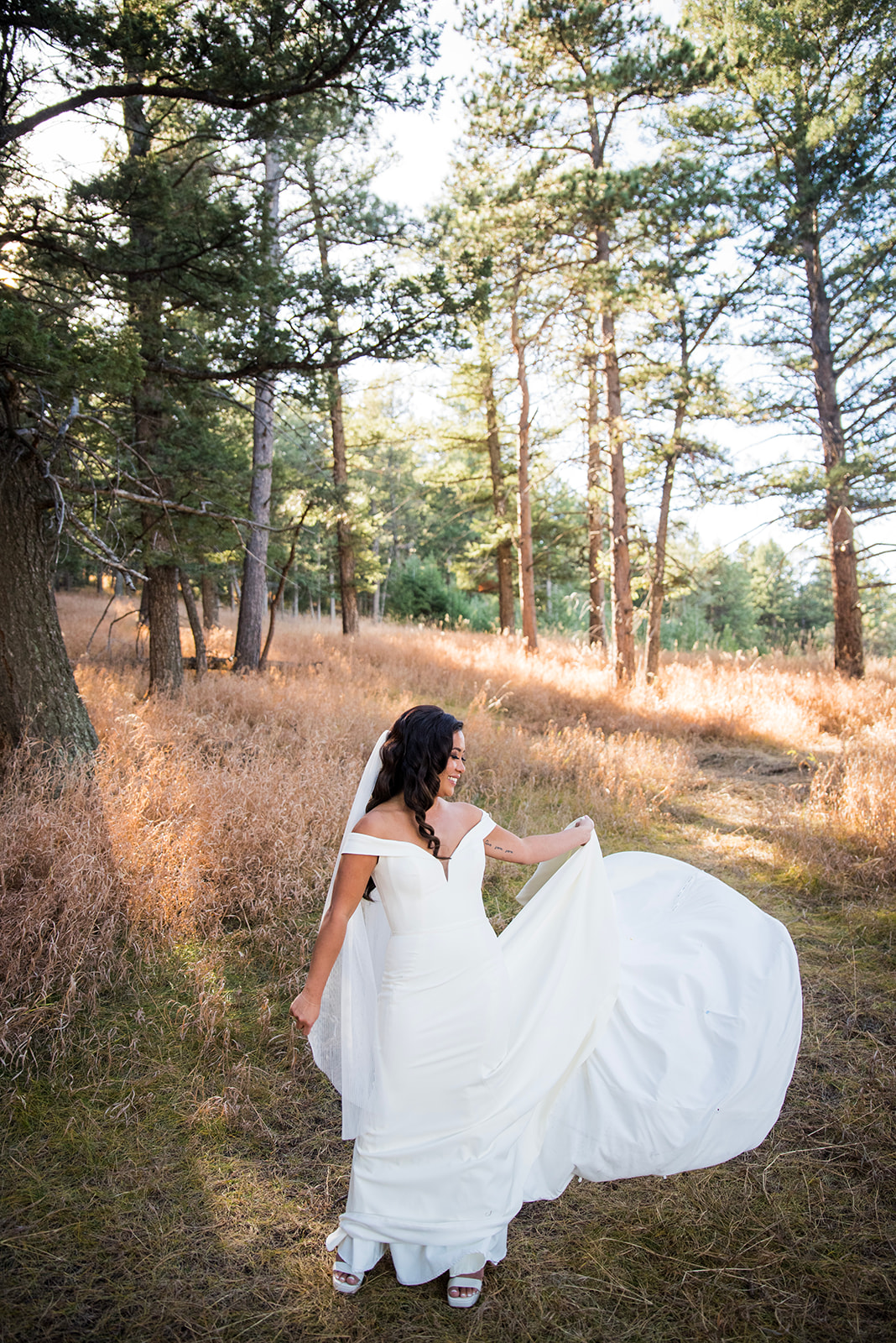 A bride twirls the skirt of her dress in the pines at The Pines by Wedgewood Weddings in Genesee, Colorado.