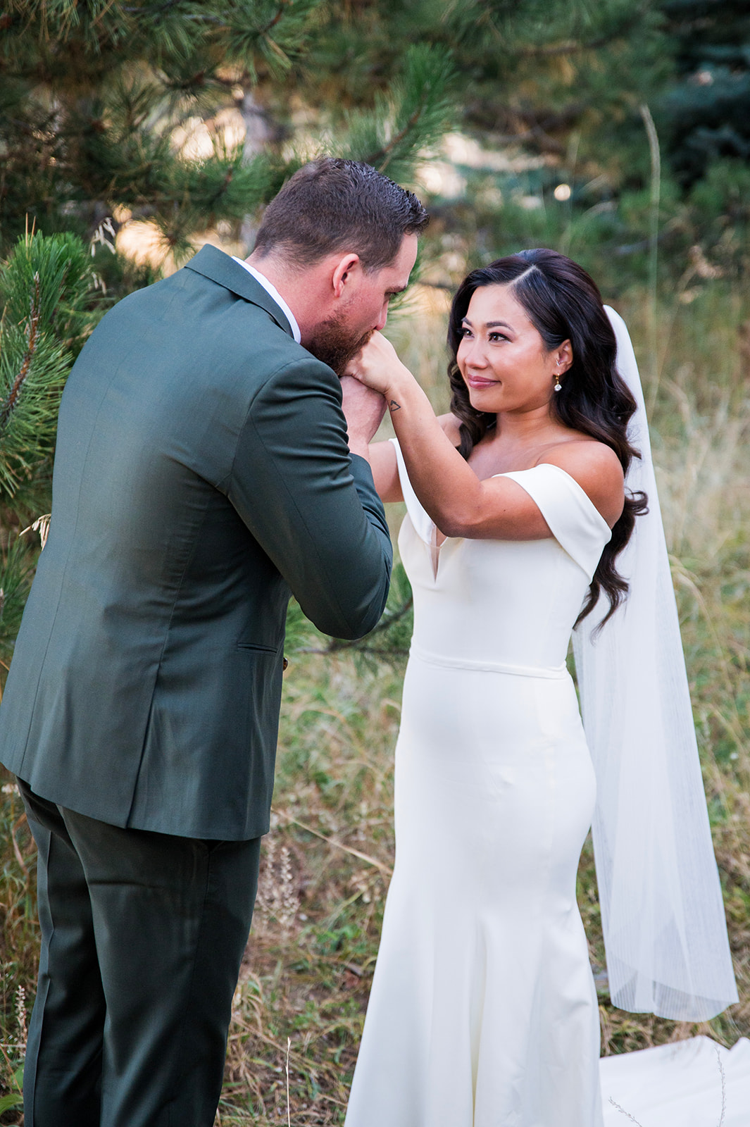 A groom romantically kisses his bride on the hand, captured by Denver wedding photographer, Two One Photography.