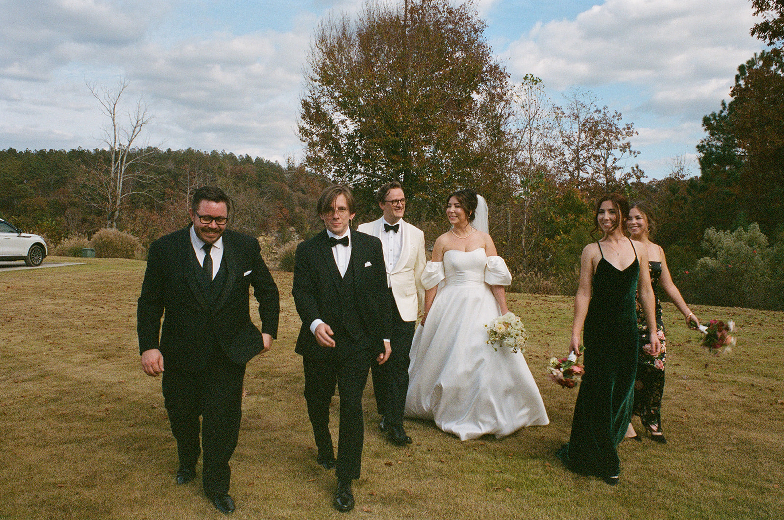 A couple walks with their bridal party during wedding day at The Barn at Smith Lake in Alabama