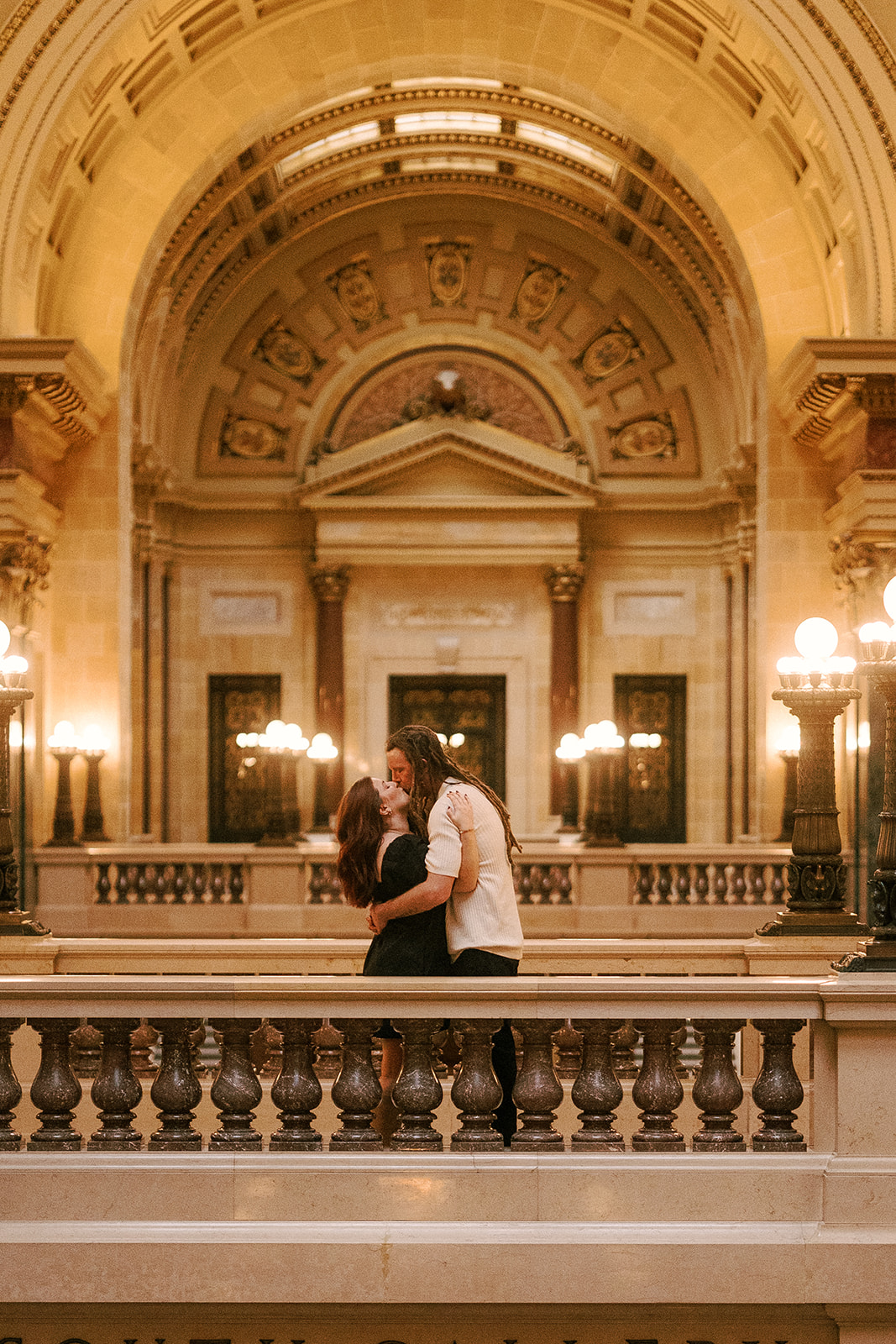 an engaged couple embraces in the Wisconsin State Capitol building in Madison