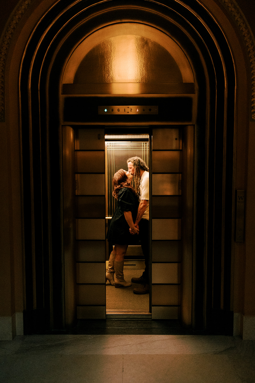 an engaged couple kisses in the elevator at the Wisconsin State Capitol building in Madison