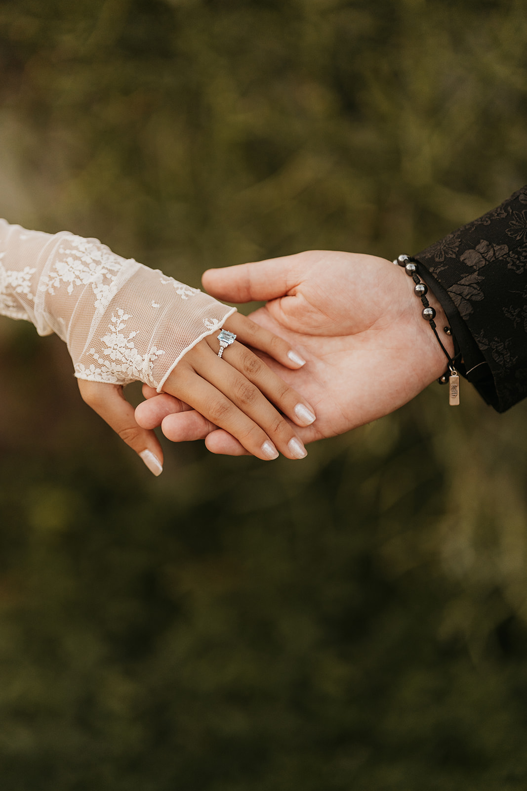 A man and woman holding hands, close up on their engagement ring 