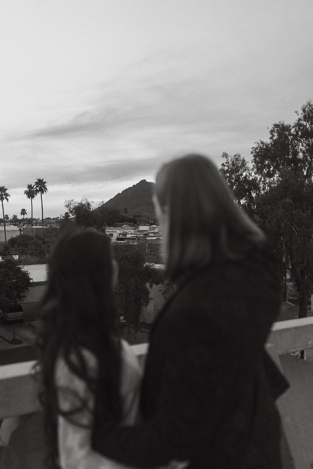 A man and woman looking out at the view of Camelback mountain at sunset 