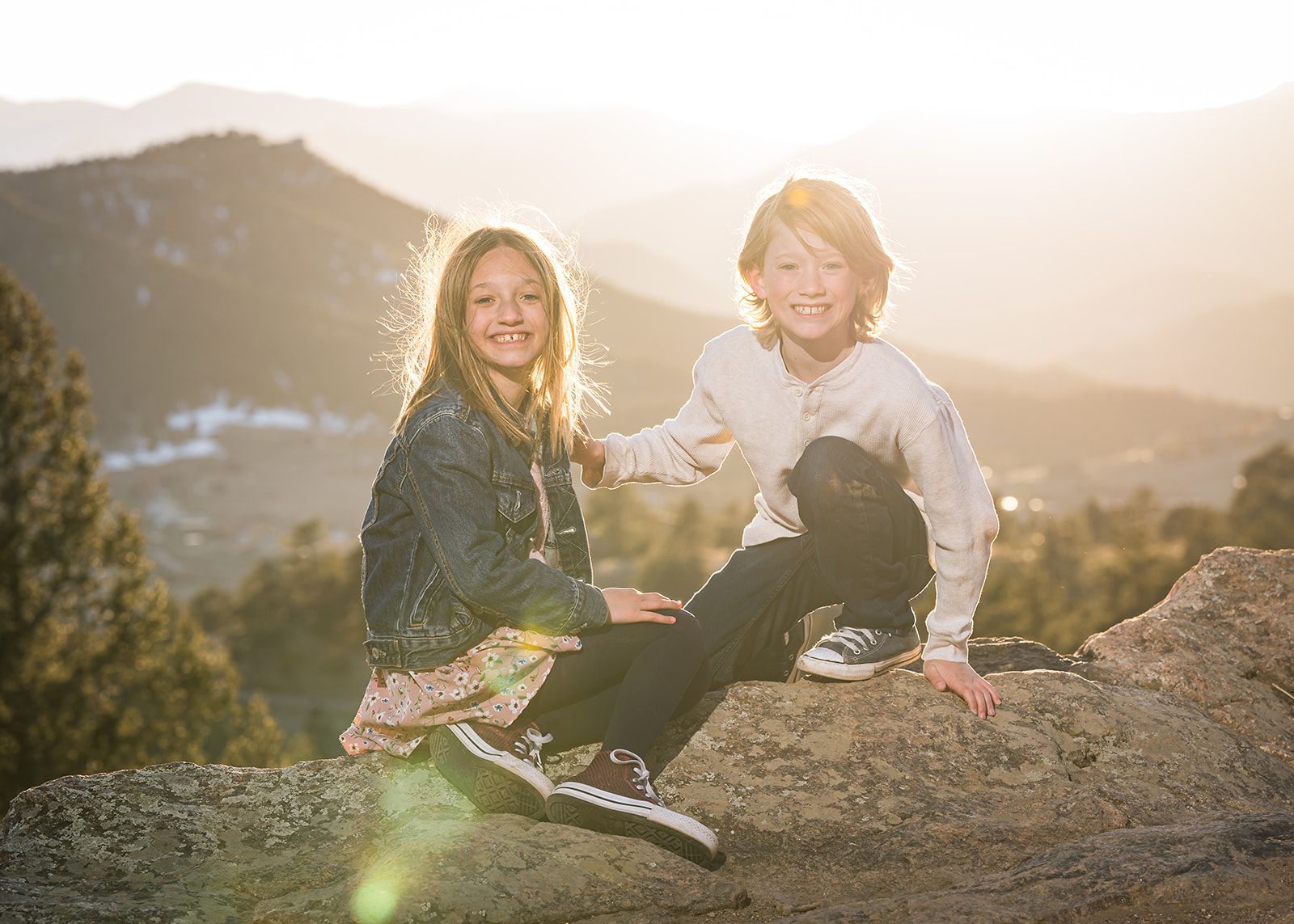 brother and sister portrait on a rock cliff with sunset behind them denver family photography