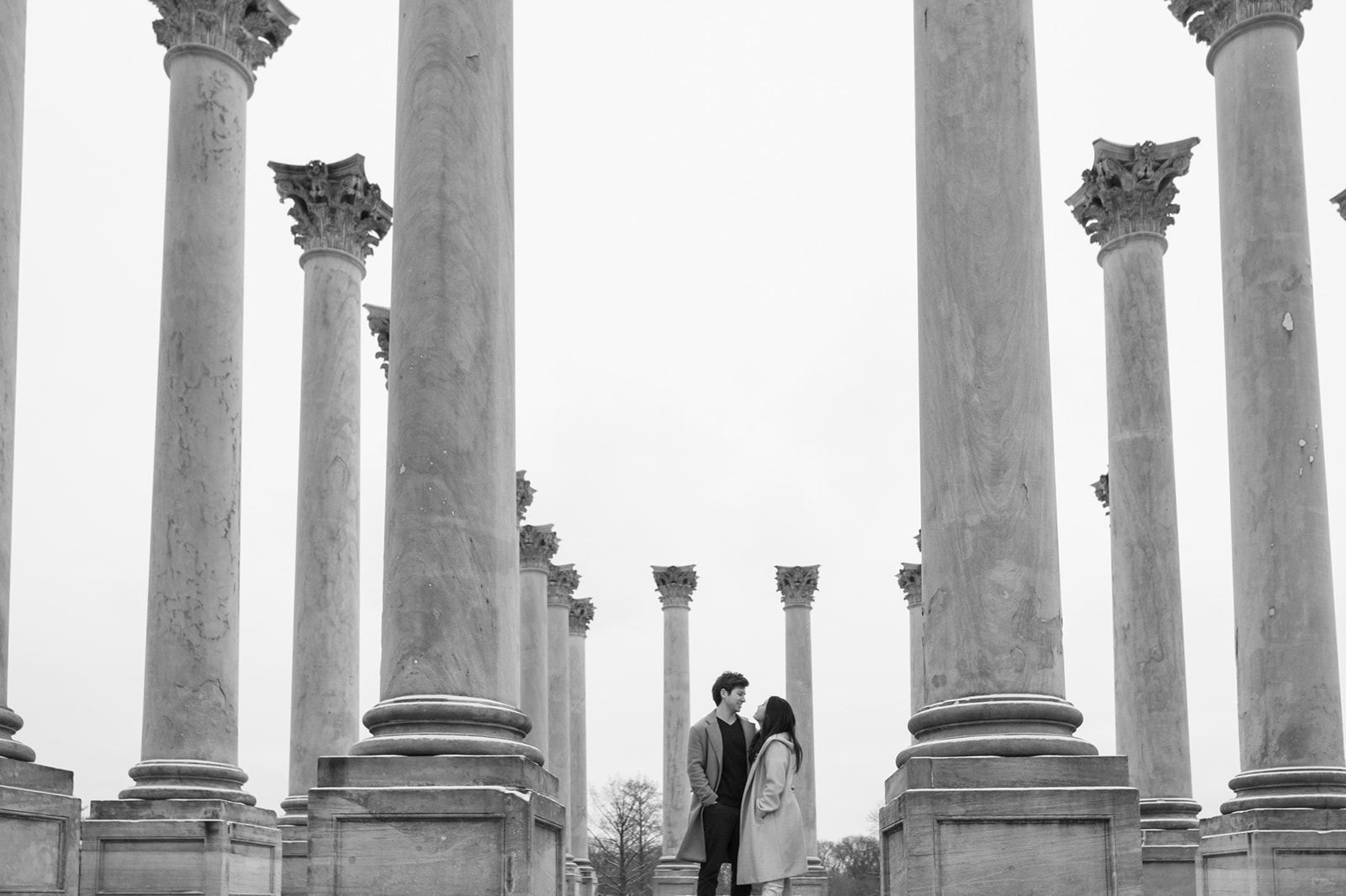 Couple stands between enormous columns at National Arboretum