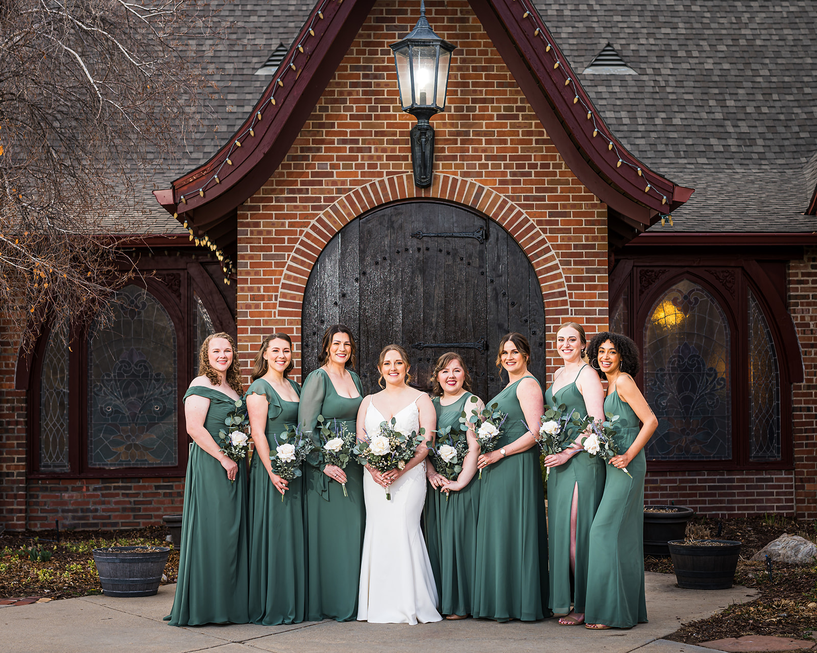 bridal party wellshire event center front of venue historical door and light flowers green dress 