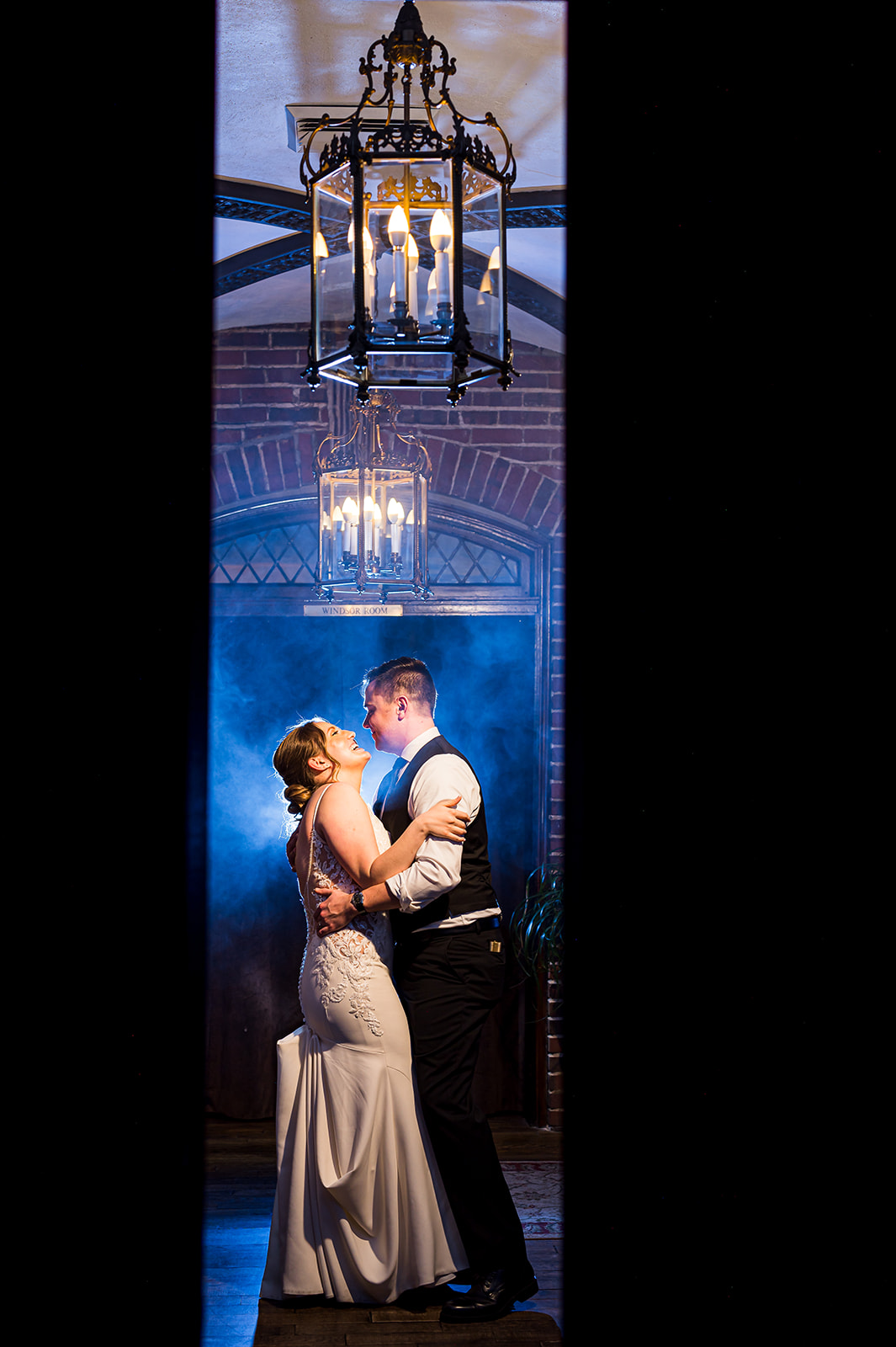 wellshire event center wedding couple with dreamy blue smoke behind them enbracing each other under chandelier