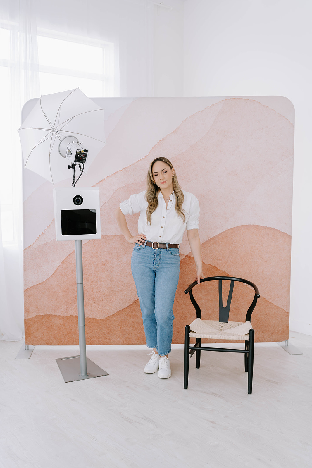 woman standing with a chair in front of photo booth backdrop